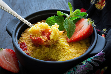 Homemade strawberry crumble on dark wooden background