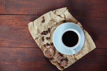 broken chocolate macaroons and coffee in mug on wooden table bac