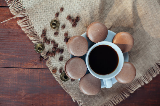 chocolate macaroons,beans and coffee in mug on wooden table back