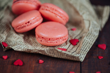 Obraz na płótnie Canvas Pink French macaroons with hearts on wooden table.Saint Valentin