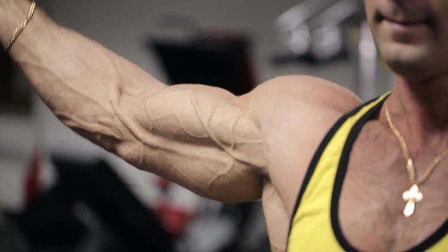Man with an intense expression on his face training in the gym his biceps and triceps