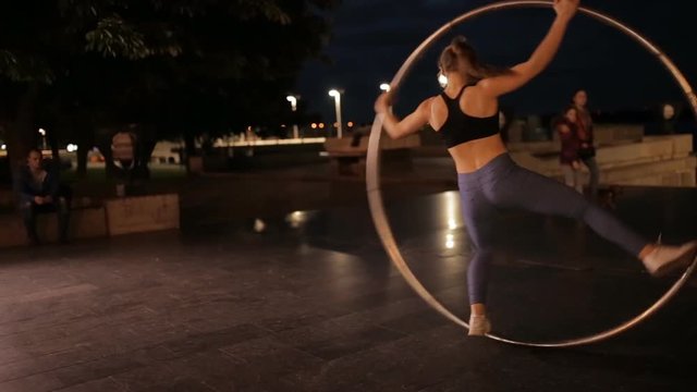 Woman on cyr wheel in city lights