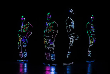 Fototapeta na wymiar dancers in led suits on dark background, colored show