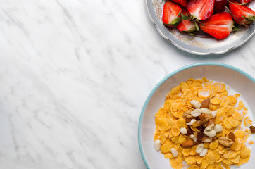 Corn flakes with berries and nuts on a marble table