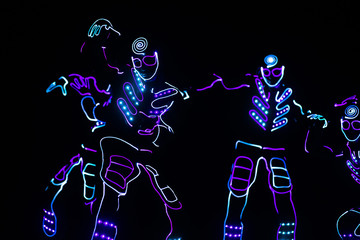Obraz na płótnie Canvas dancers in led suits on dark background, colored show