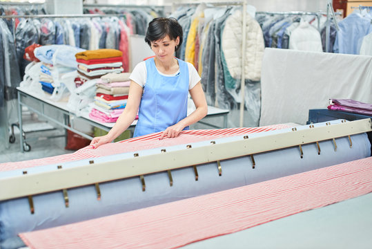 Woman Laundry worker pats the linen on the automatic machine at the dry cleaners