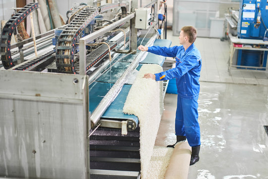 Laundry worker in the process of working on automatic machine for carpet washing in dry cleaning