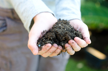 Childs hands holding a handful of soil outside