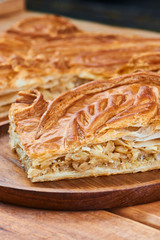 A piece of pie with filling their cabbage on wooden plate