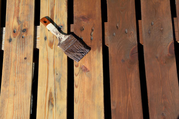 Paintbrush with brown paint on planks