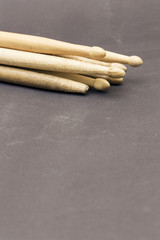 A group of used wooden drumsticks, on a black drum patch.
