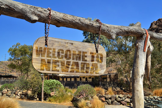 old wood signboard with text " welcome to nevada" hanging on a branch