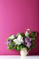 Blooming lilac flowers in the basket on pink background