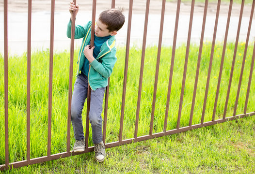 illegally entering. child crawls through the bars of the iron fence