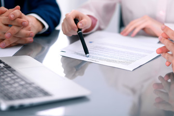 Group of business people and lawyers discussing contract papers sitting at the table, close up