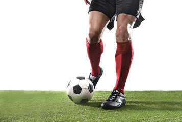 football player in red socks and black shoes running and dribbling with the ball playing on grass