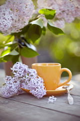 Bouquet of a lilac and cup with a spoon