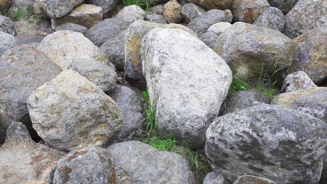 Group of big boulder stones lying in field, natural geologic background, panning view