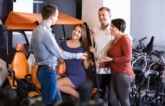 Male Employee Helping Family To Select Tour Electrics