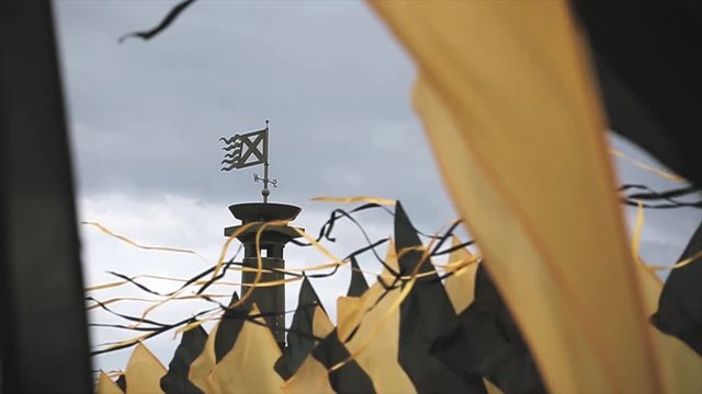 Black and yellow flags waving from wind in summer day. Festival. Grey sky before heavy rain. Column with flag. Slow motion. 