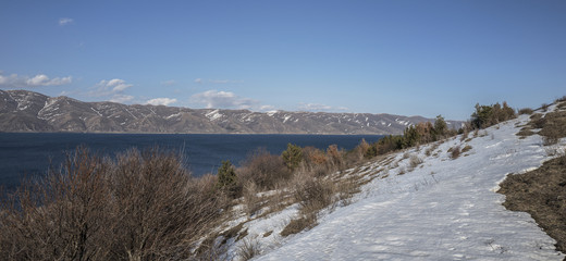 Panoramic view of Sevan Lake with snow maintains around of it