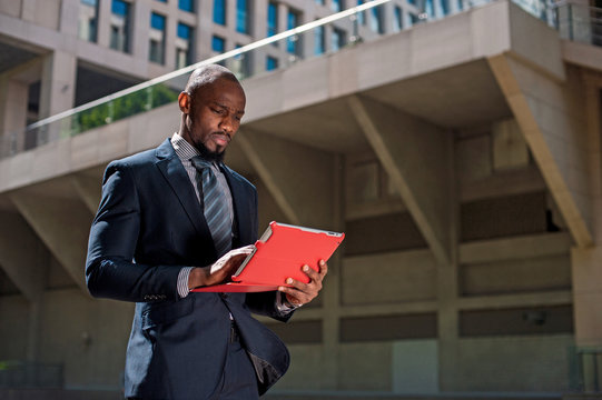 black businessman looking at his tablet computer in urban backgr