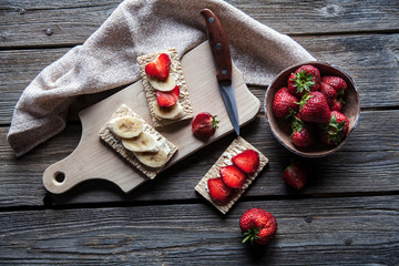 Fruity toast on wooden background. Strawberries, bread, butter and cheese.Vintage style
