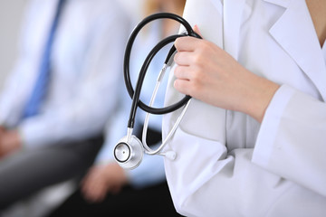 Doctor holding a stethoscope in his hands , the patient on the background