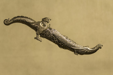 decorative carved dagger with heads of dragons in a sheath on a gray background