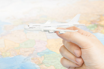 Travelling, tourism, communications and all things related - studio shot of toy aircarft in hand with world map on background