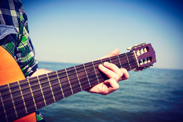 Guitarist playing next to sea.