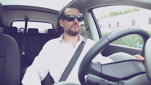 Serious man with white shirt driving car with sun glasses retro style