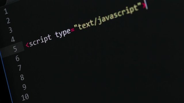 JavaScript programmer writing a function, code editor window and computer screen shot under a slight angle