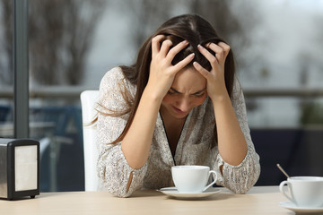Sad and depressed woman alone in a coffee shop - obrazy, fototapety, plakaty