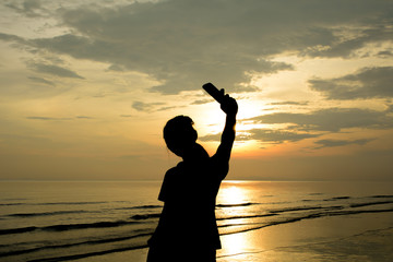 Fototapeta premium Woman silhouette selfie. Background sunset on the sea