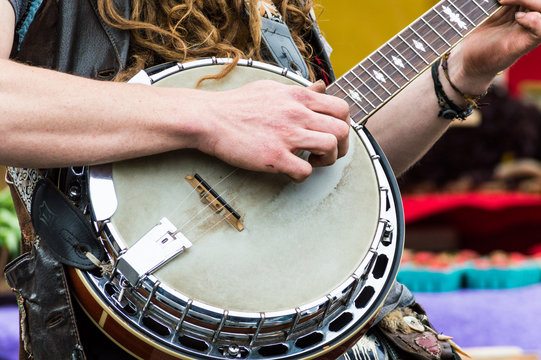 Close up of a banjo player playing music for an audience at a farmers market.