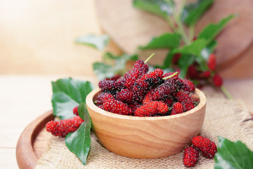 fresh organic mulberry in bowl on wooden background with mulberry fruit and mulberry branch. 