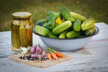 Cucumbers in metal bowl, vegetables and spices for pickling and jar pickled cucumbers