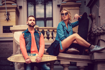 Modern casual couple posing with skateboard.