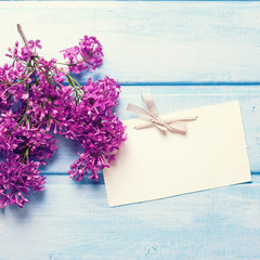 Fresh lilac flowers  and empty tag on blue wooden planks.