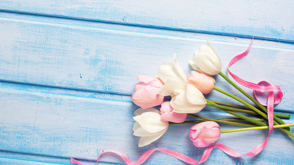 White and pink spring tulips and  pink ribbon  on  blue wooden b