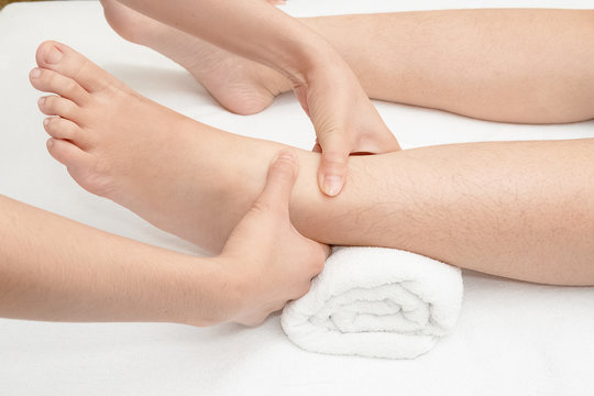 Foot massage, therapist's hands massaging female foot