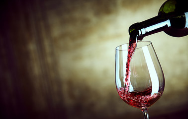 Fototapeta na wymiar Serving a single glass of red wine from a bottle