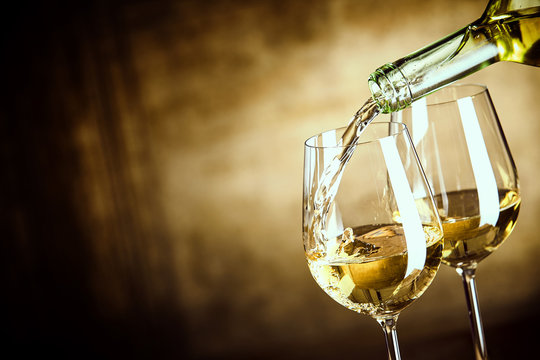 Fototapeta Pouring two glasses of white wine from a bottle