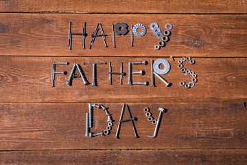 Happy father's Day! Greeting gard made of tools, iron nuts and bolts. Wooden background