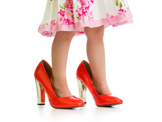 kid girl trying mother's shoes on her legs