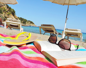 Reading at the beach. Sunglasses and book, selective focus. © eivaisla
