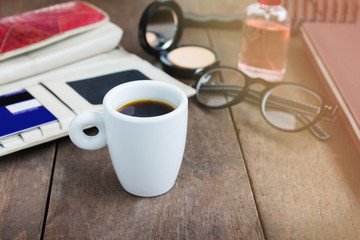 White cup hot black coffee on wood table with working women things, lady with morning rush hour coffee time