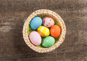 Easter eggs in nest on color wooden background