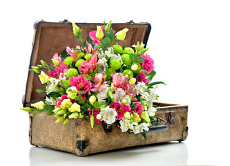 A bunch of beautiful flowers in an old shabby suitcase. Isolated